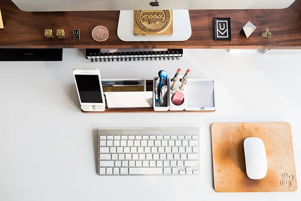 Overhead desk layout with keyboard, mouse, phone and stationery.